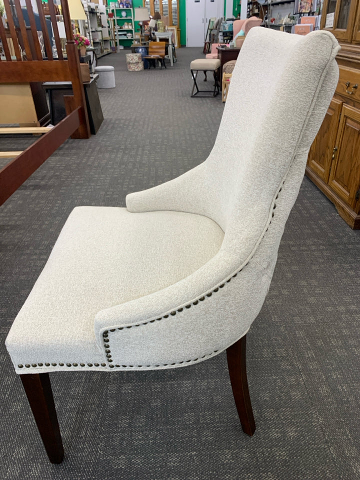 UPHOLSTERED CREAM CHAIR W/DARK WOODEN LEGS.