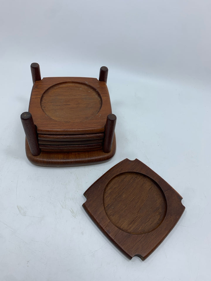 6 CARVED WOODEN COASTERS IN HOLDER.