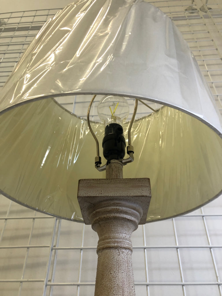 GRAY DISTRESSED LAMP WITH WHITE LAMP SHADE.