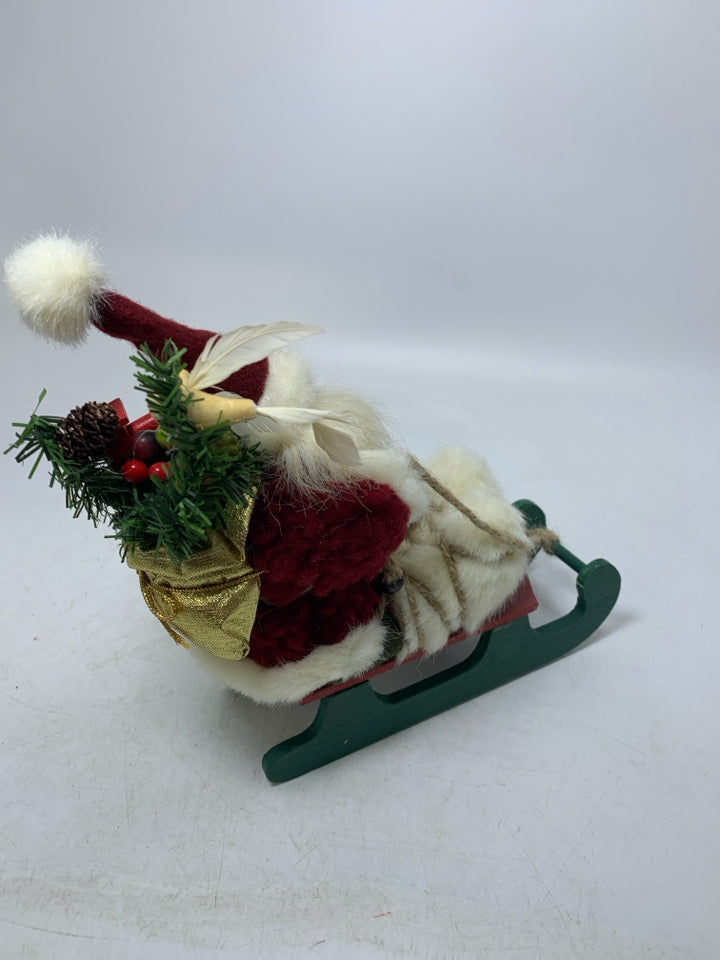 SMALL PLUSH SANTA ON GREEN SLED.