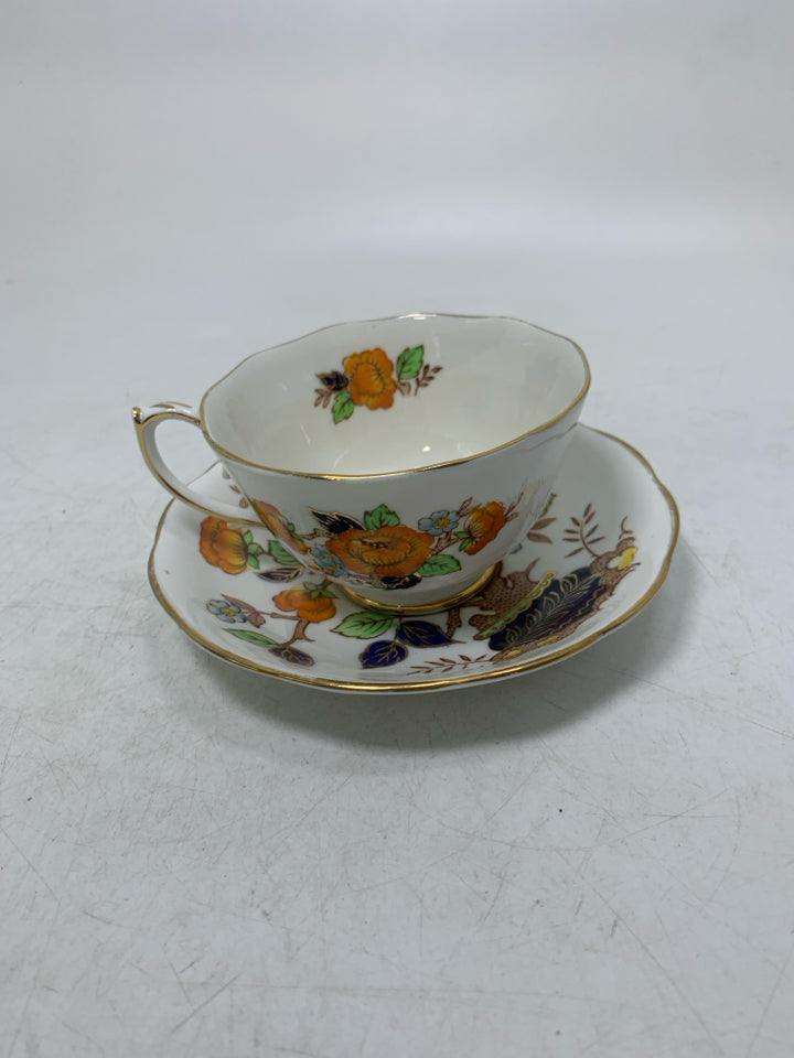 ORANGE FLOWERS IN PLANTER W/ GOLD RIM.