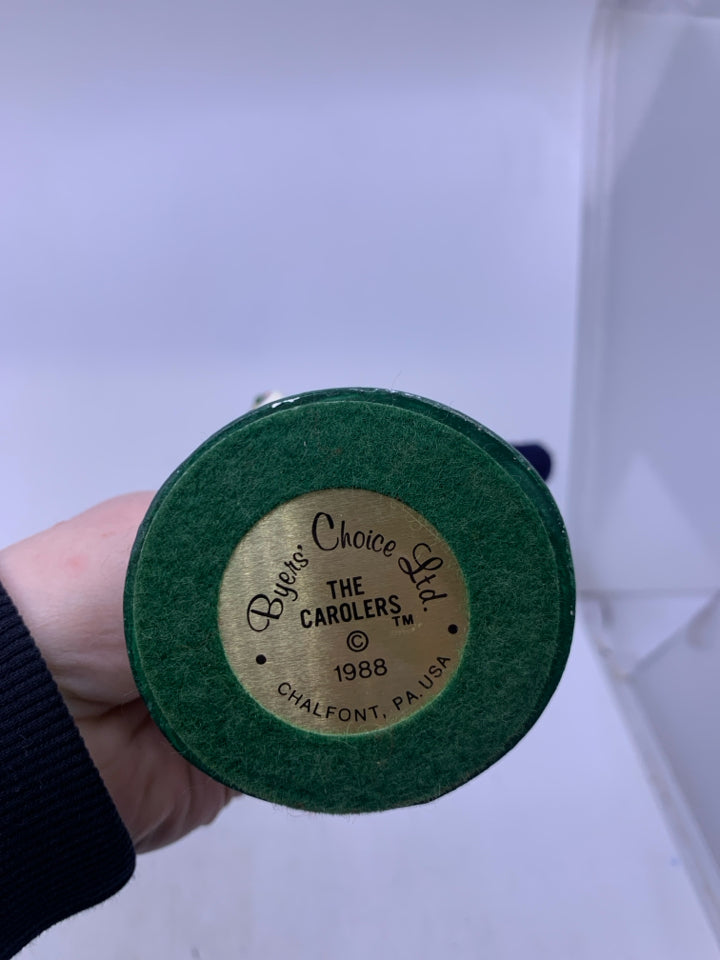 GIRL CAROLER W/ DARK BLUE COAT HOLDING BELL 1988 BYERS' CHOICE.