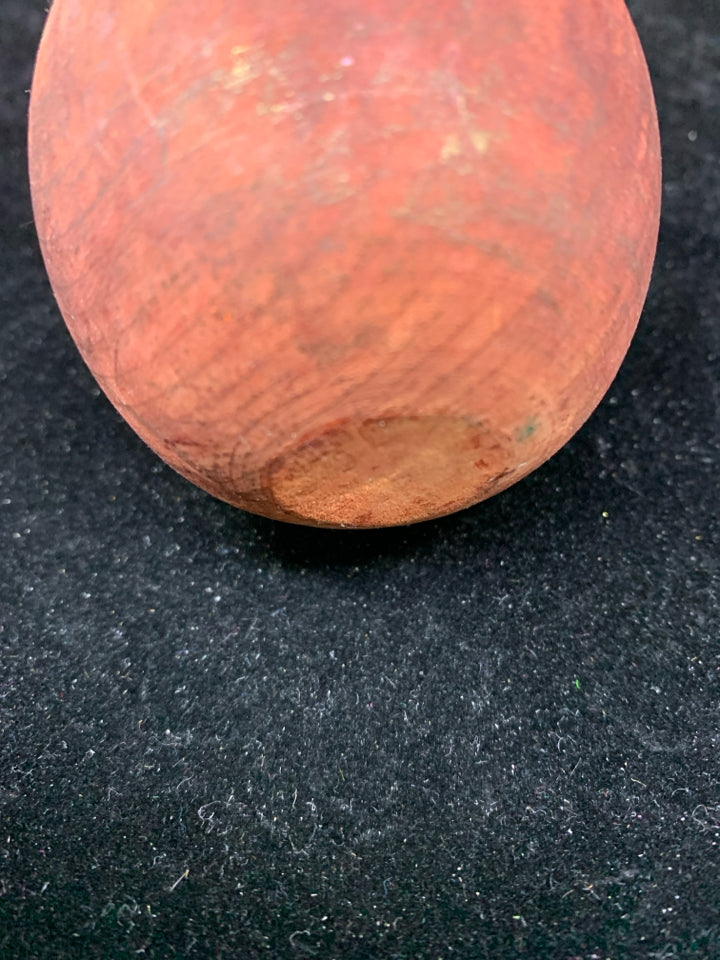 RED PRIMITIVE APPLE ON STAND.