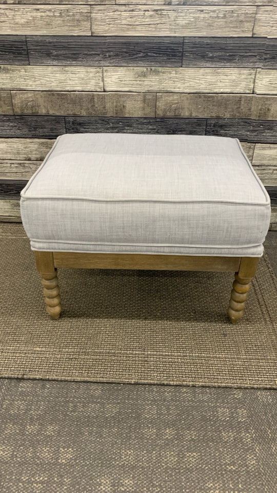 GREY OTTOMAN W/SPIRAL WOODEN LEGS.