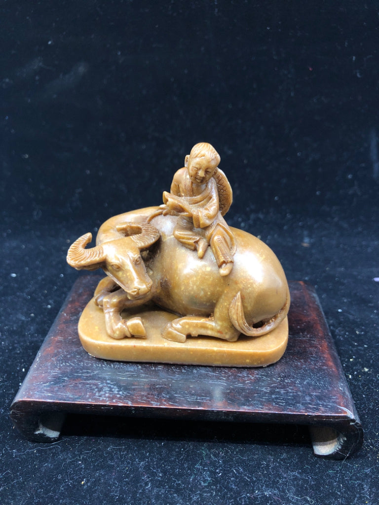 BROWN BULL & MAN FIGURINE ON WOOD SLAB.