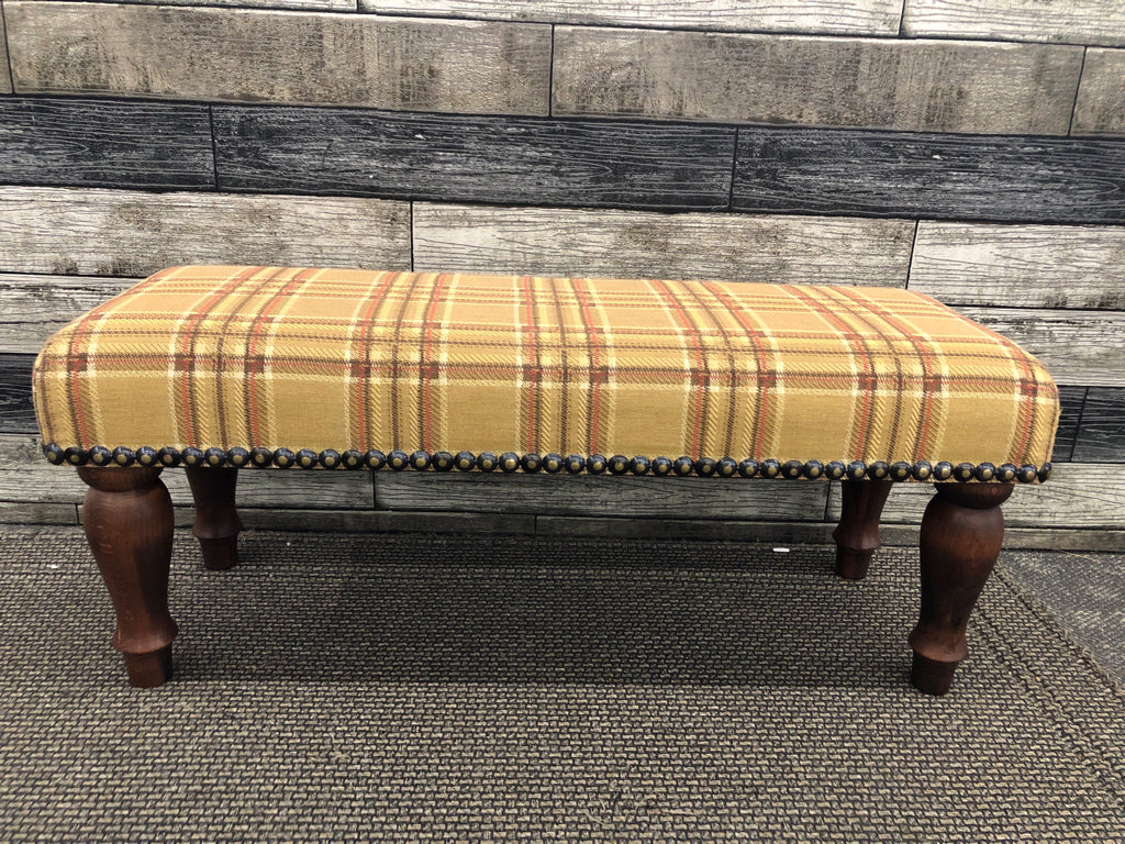 PLAID FOOTSTOOL W/DARK WOOD LEGS.