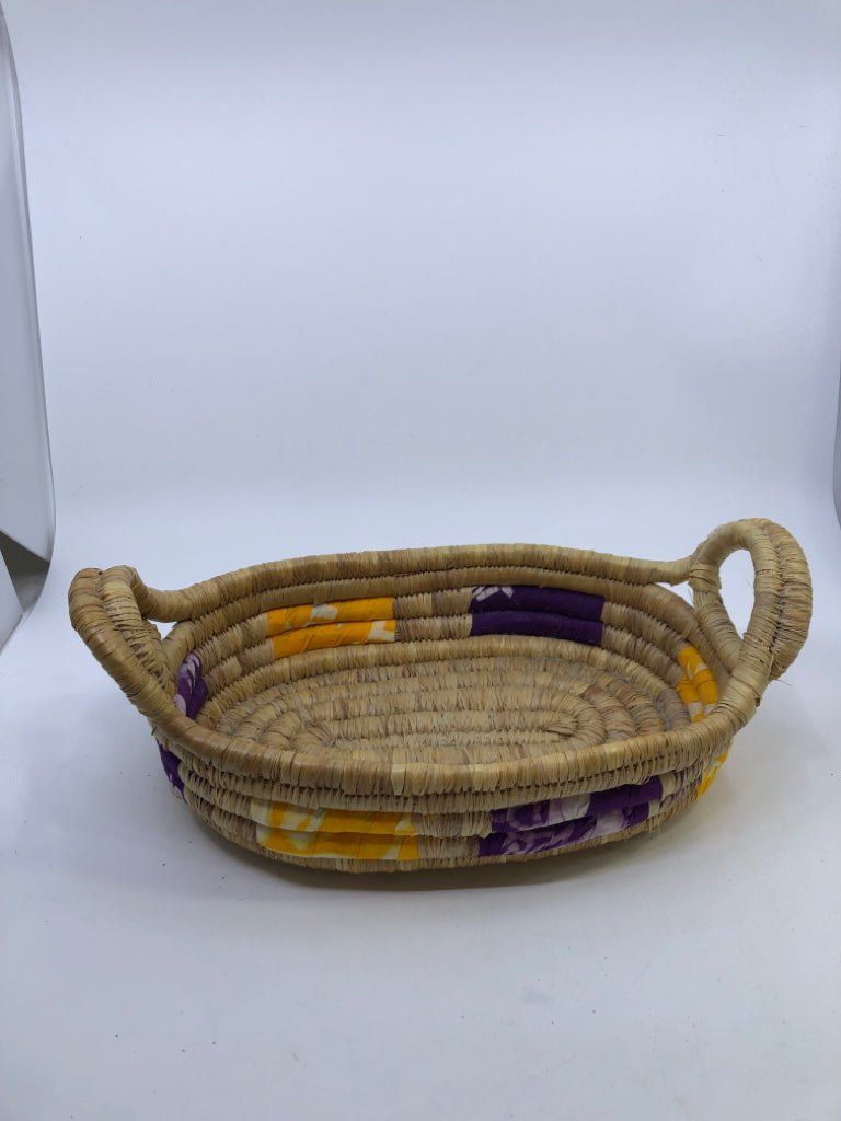 SWIRLED WICKER BASKET W/YELLOW AND PURPLE CLOTH & HANDLES.
