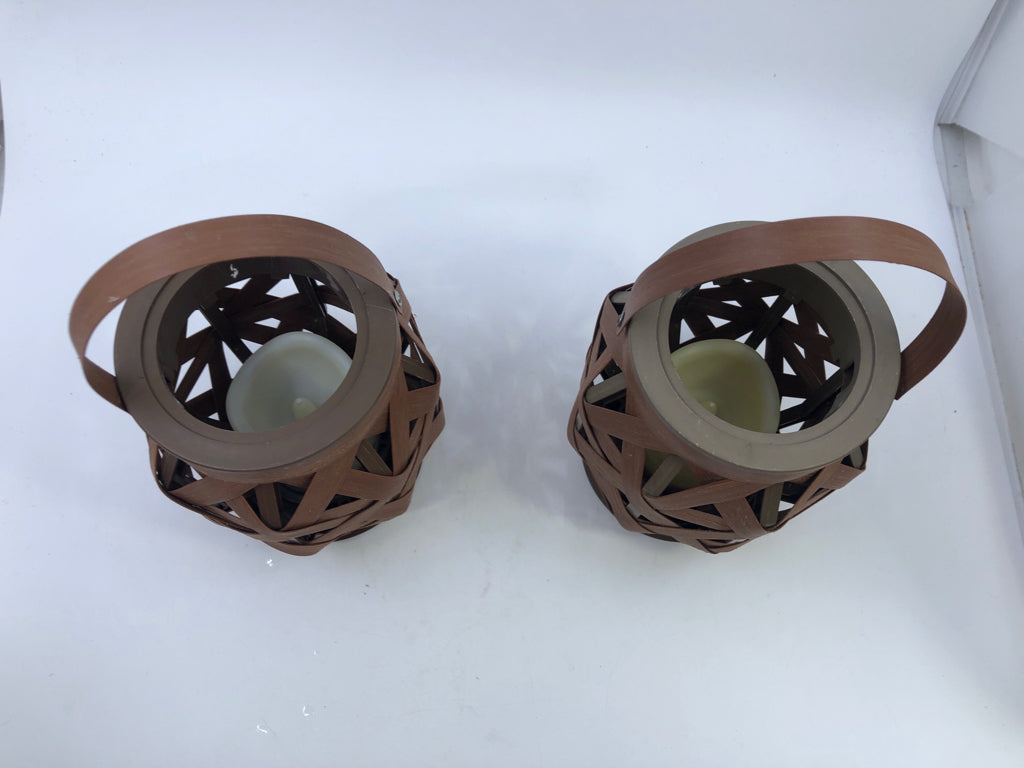 2 BROWN OPEN WEAVE LANTERNS WITH HANDLES AND BATTERY OPERATED CANDLES.