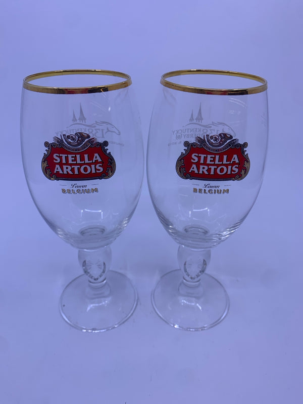 2 STELLA ARTOIS FOOTED GLASSES W/ GOLD RIM.