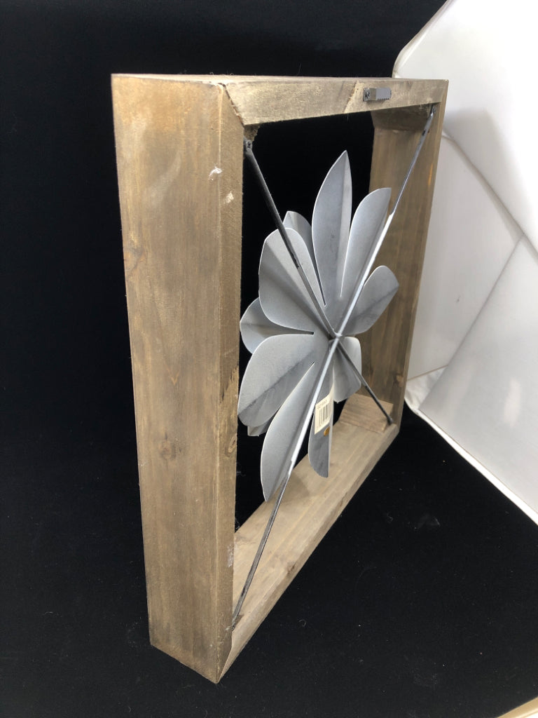WHITE METAL FLOWER SUSPENDED IN WOOD FRAME.