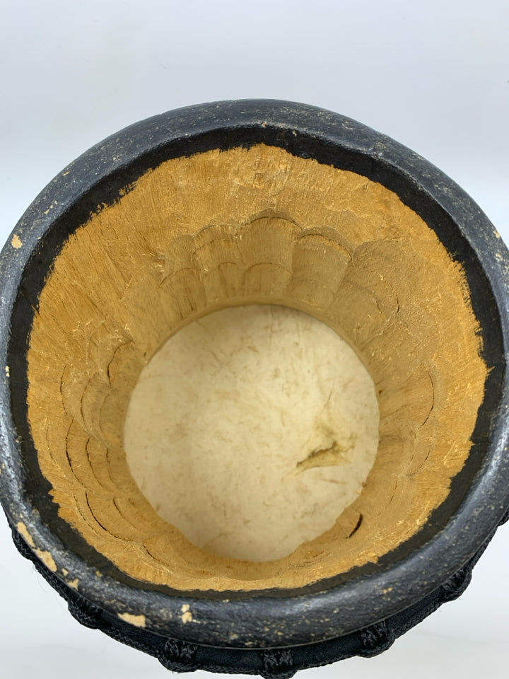 LIGHT COLORED DRUM W/BLACK ROPE.
