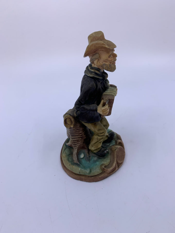 MAN PLAYING ACCORDION LEANING ON TREE.