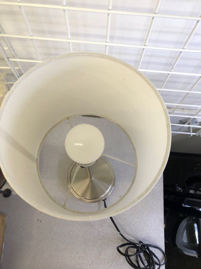 SKINNY SILVER METAL BASE LAMP W/ WHITE SHADE.