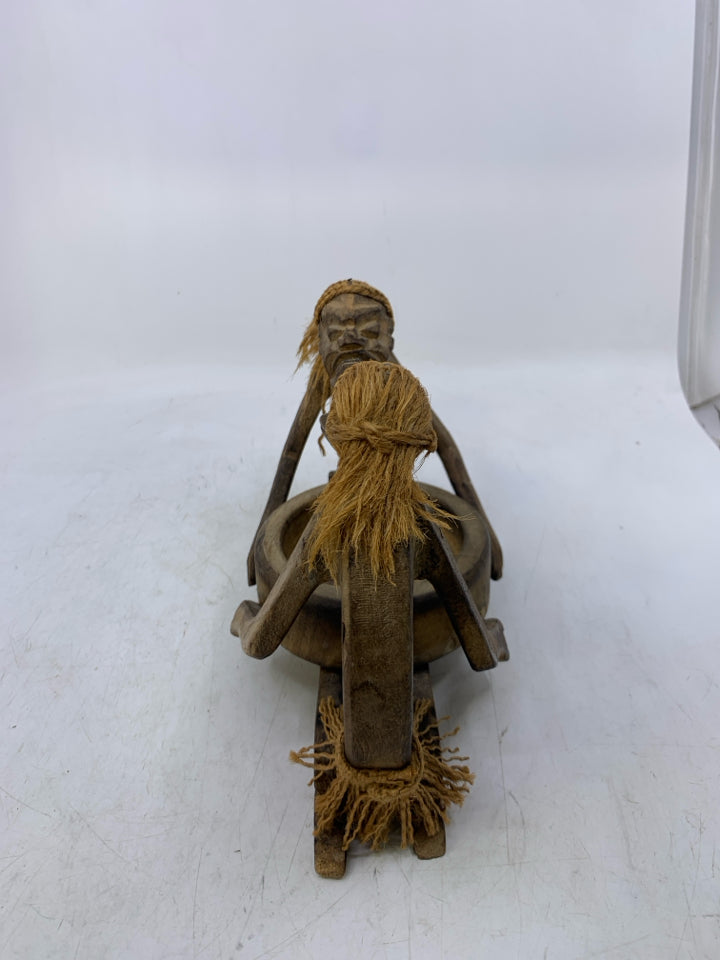 CARVED MEN LOOKING AT EACHOTHER KNEELING W/ BOWL.