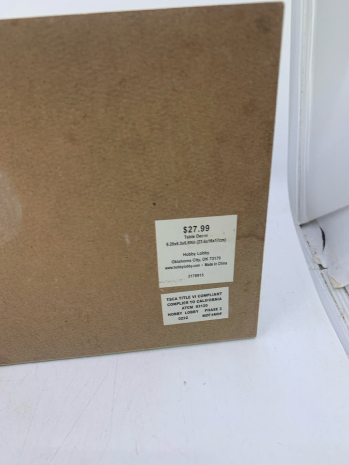 WHITE 2 STACKED BOOKS W/ HI ON TOP.