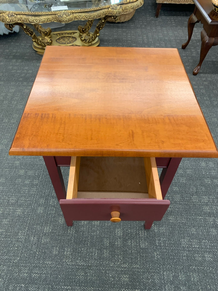 CHERRY WOOD SIDE TABLE W/DRAWER AND RED PAINTED LEGS.