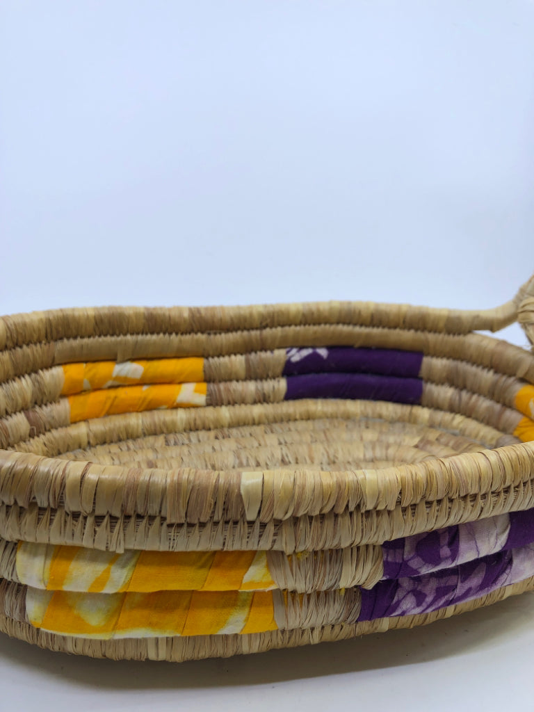 SWIRLED WICKER BASKET W/YELLOW AND PURPLE CLOTH & HANDLES.