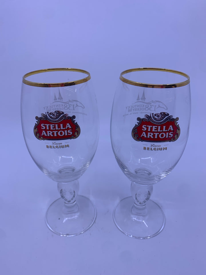 2 STELLA ARTOIS FOOTED GLASSES W/ GOLD RIM.