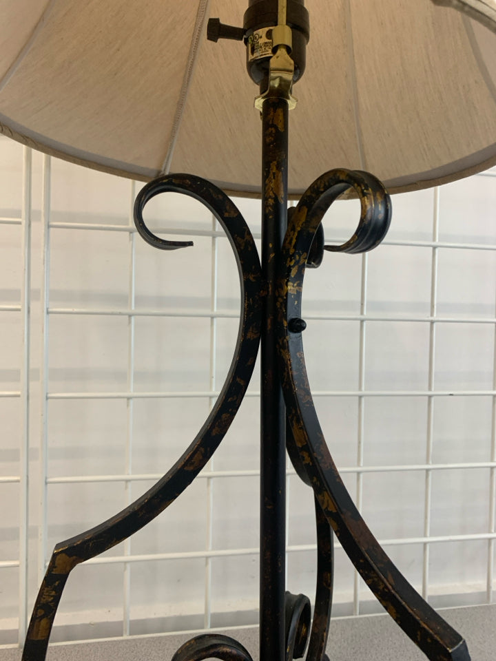 BLACK SCROLL BASE LAMP W/GOLD FLECKS AND TAN SHADE.