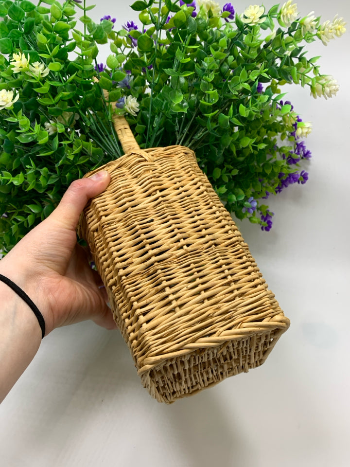 FAUX PURPLE AND GREENERY IN WICKER BASKET.