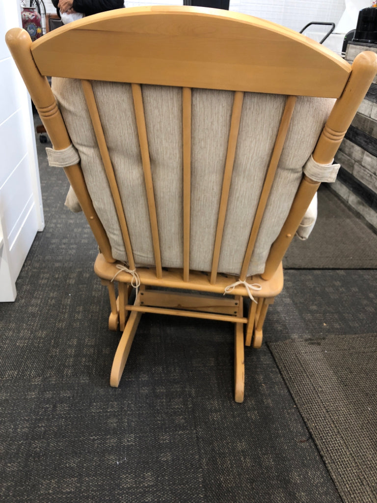 BLONDE WOODEN ROCKING CHAIR W/LEVER TO LOCK & BEIGE CUSHION.