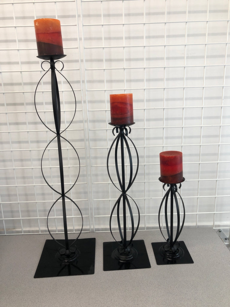 3 DECORATIVE CANDLE HOLDERS W/ORANGE TO RED CANDLES.