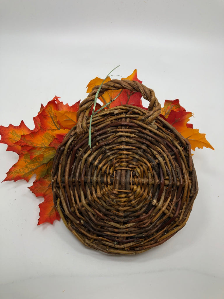 ORANGE LEAVES IN BROWN WICKER HANGING BASKET.
