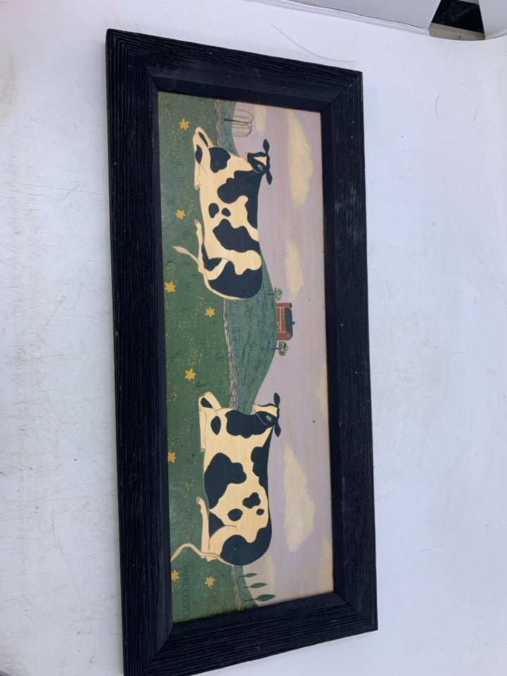 PRIMITIVE STYLE 2 COWS LAYING DOWN IN FIELD.