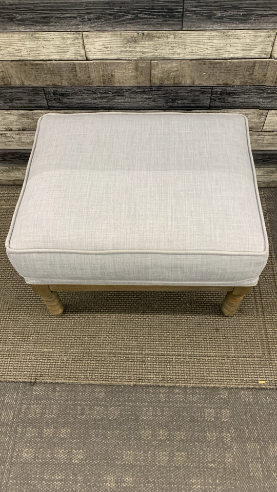 GREY OTTOMAN W/SPIRAL WOODEN LEGS.
