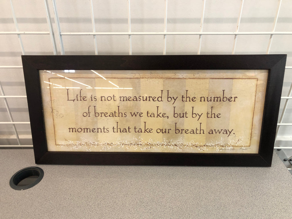 LIFE IS MEASURED WALL ART IN BROWN WOOD FRAME.