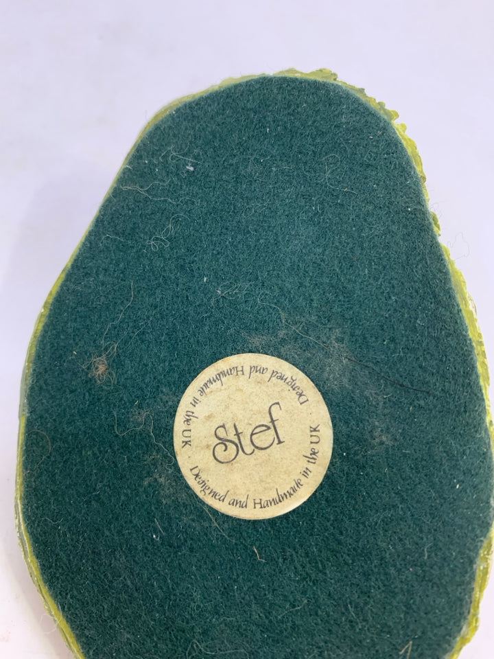 CERAMIC SITTING LIGHT BROWN/WHITE COW ON GRASS.