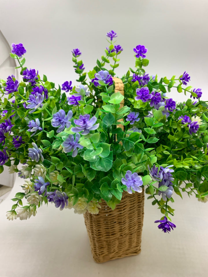 FAUX PURPLE AND GREENERY IN WICKER BASKET.
