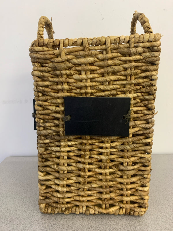 TALL WOVEN BASKET WITH CHALK BOARD LABELS AND HANDLES.