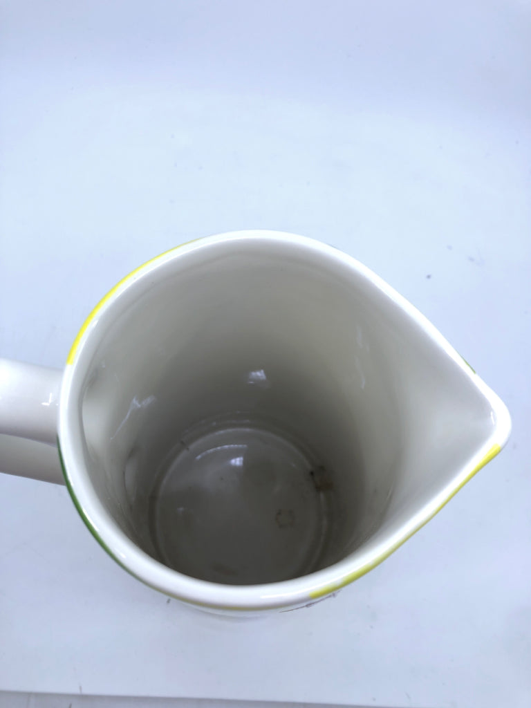 TALL WHITE CERAMIC PITCHER WITH LEMONS.