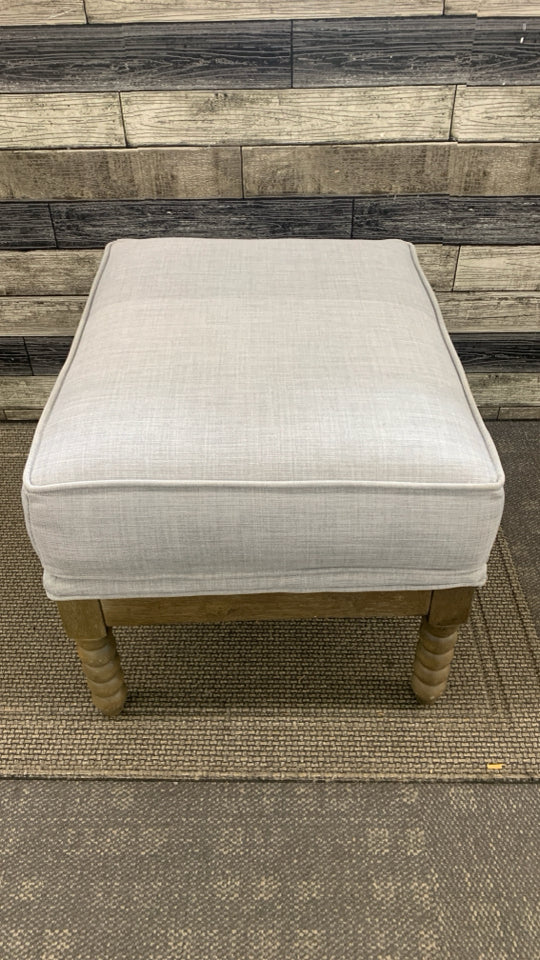 GREY OTTOMAN W/SPIRAL WOODEN LEGS.