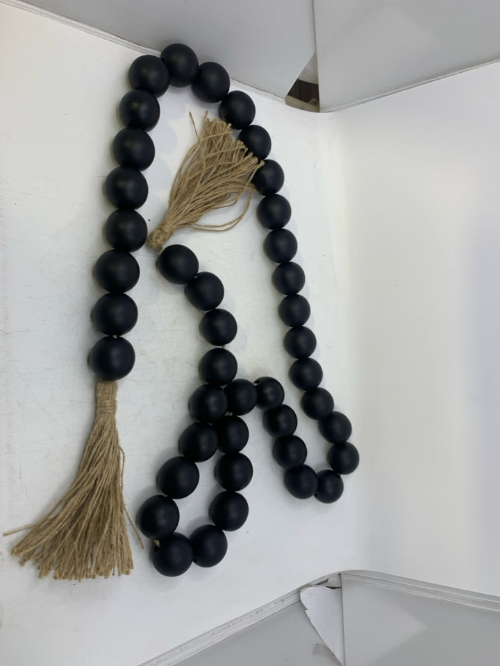 BLACK BEADS W/ TWINE TASSELS.