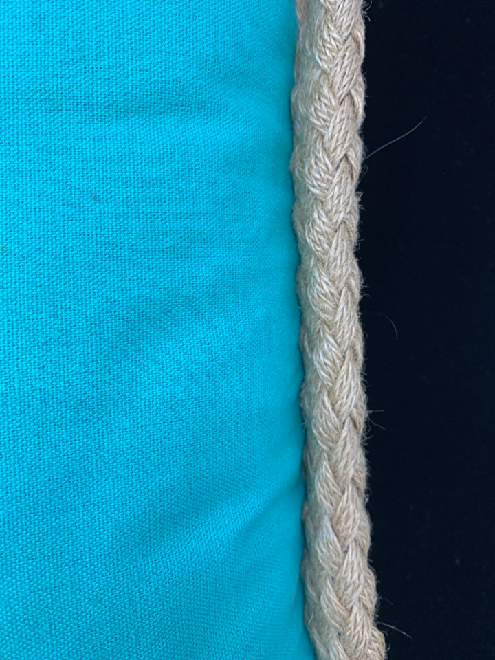 TEAL PILLOW W/WHITE DESIGN & BRAIDED BURLAP BORDER.