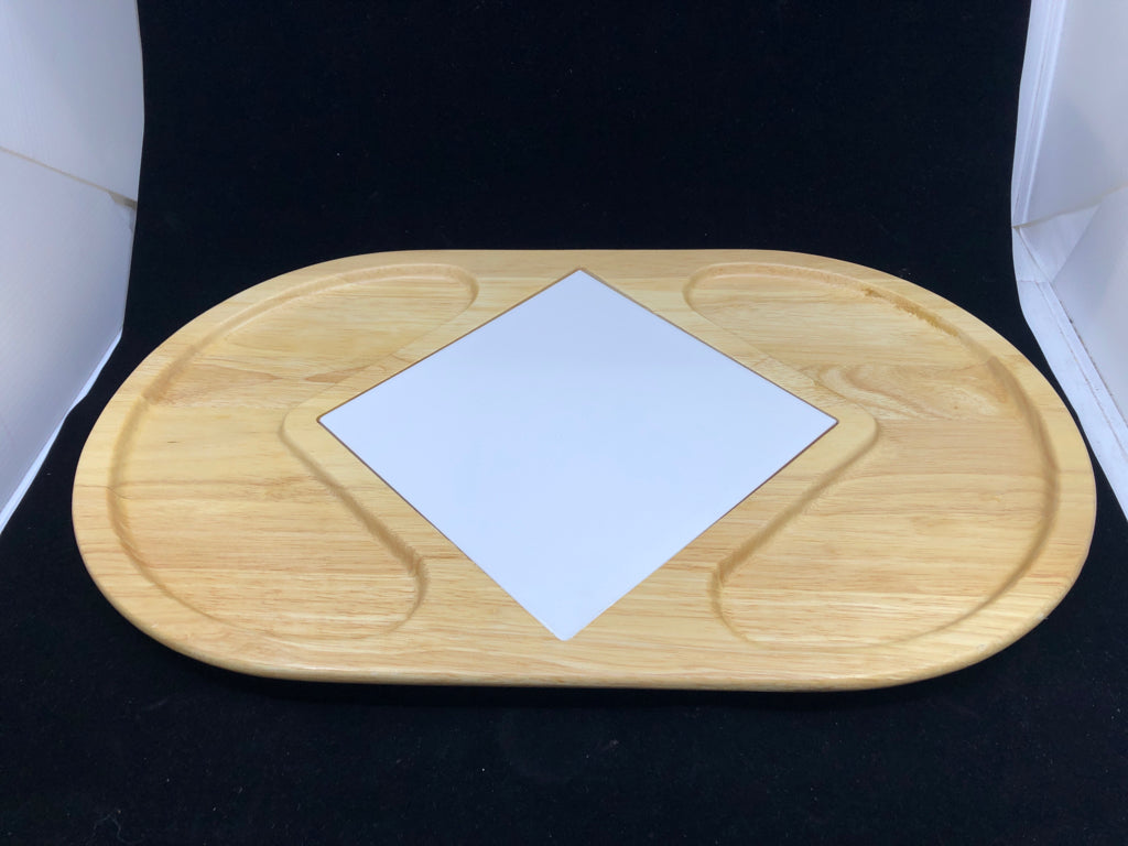 BLONDE OVAL WOOD SERVING TRAY W/ WHITE SQUARE TILE TRIVET IN CENTER.