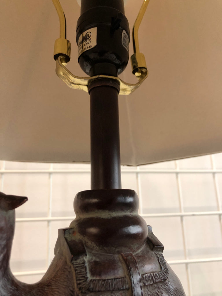 WOOD CAMEL BASE LAMP W/TAN SHADE.