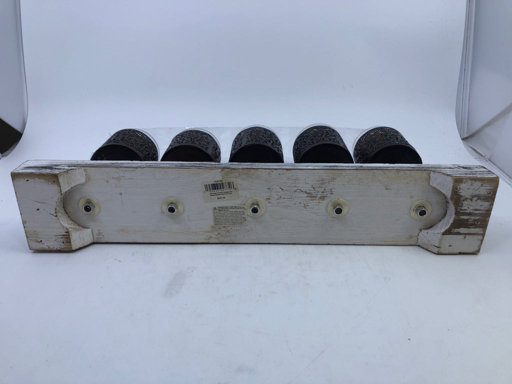 5 METAL CANDLE HOLDERS ON DISTRESSED WOOD BLOCK.