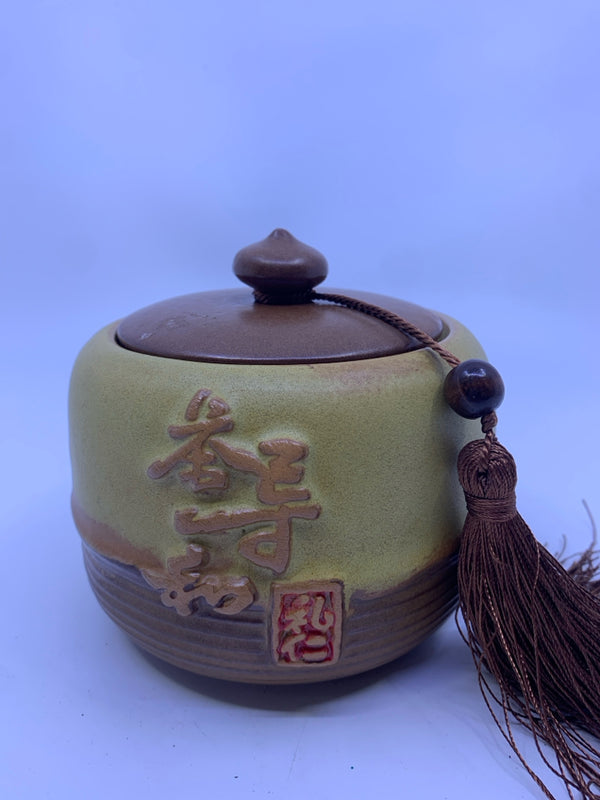 YELLOW CHINESE LETTERS CANISTER W TASSEL ON BROWN LID.