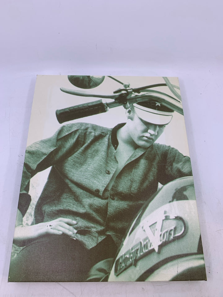 CLOSE UP OF ELVIS LOOKING AT MOTORCYCLE CANVAS.