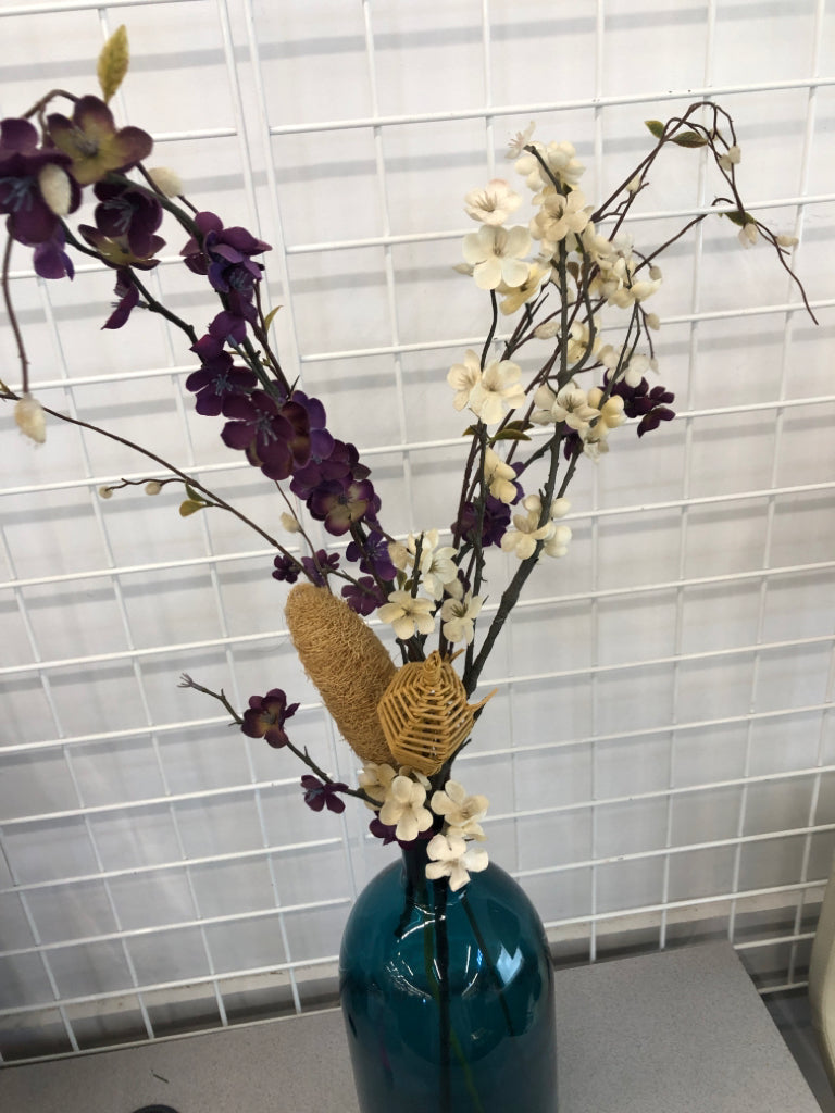 PURPLE FLORALS IN BLUE GLASS VASE.