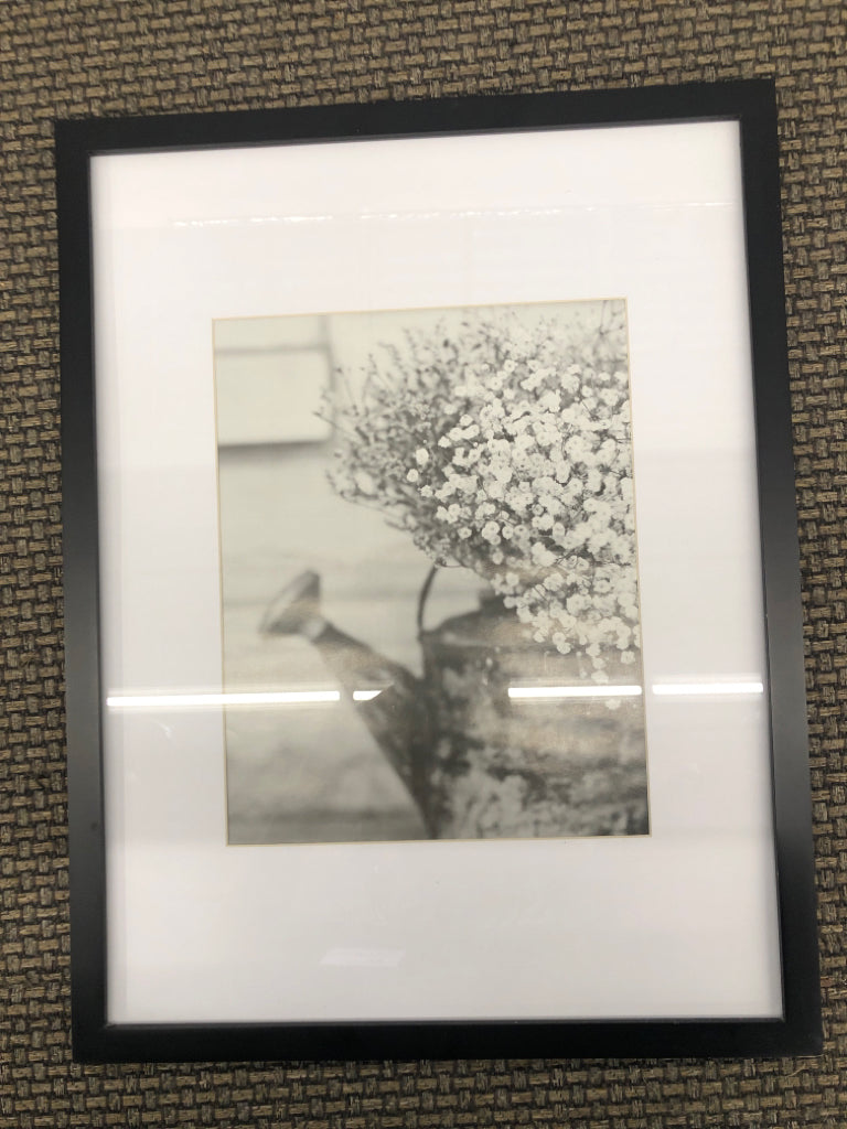 BLACK/WHITE FLOWER WATERING CAN PRINT IN BLACK FRAME.