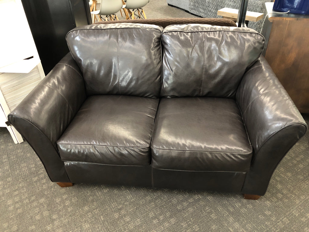 BROWN LEATHER LOVE SEAT W/2 GEOMETRIC STYLE PILLOWS.