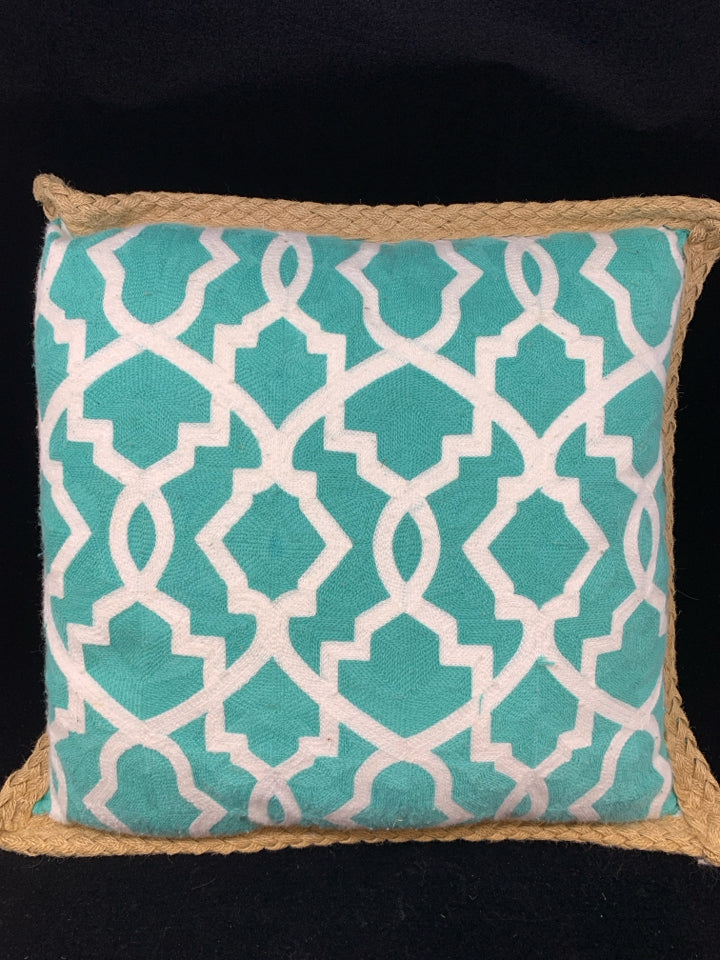 TEAL PILLOW W/WHITE DESIGN & BRAIDED BURLAP BORDER.