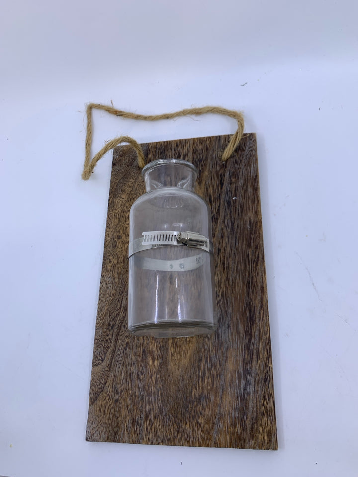 GLASS BOTTLE VASE ON PLANK.