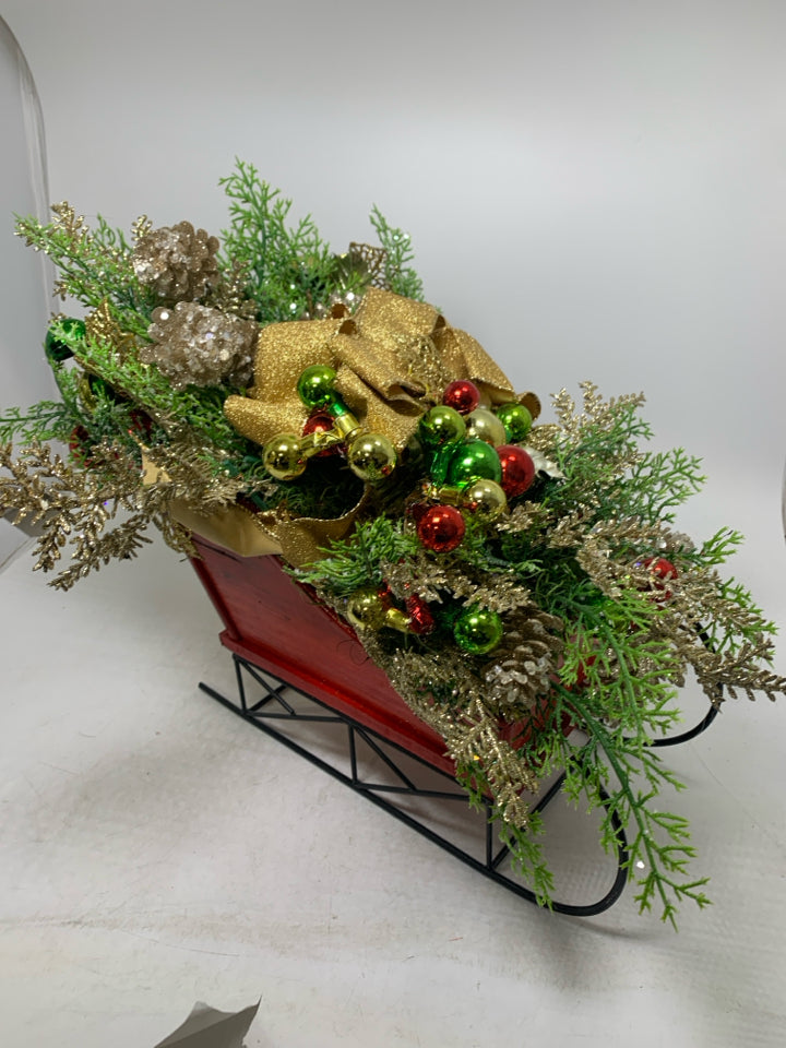 RED SLEIGH W/ HOLIDAY FLORAL ARRANGEMENT.