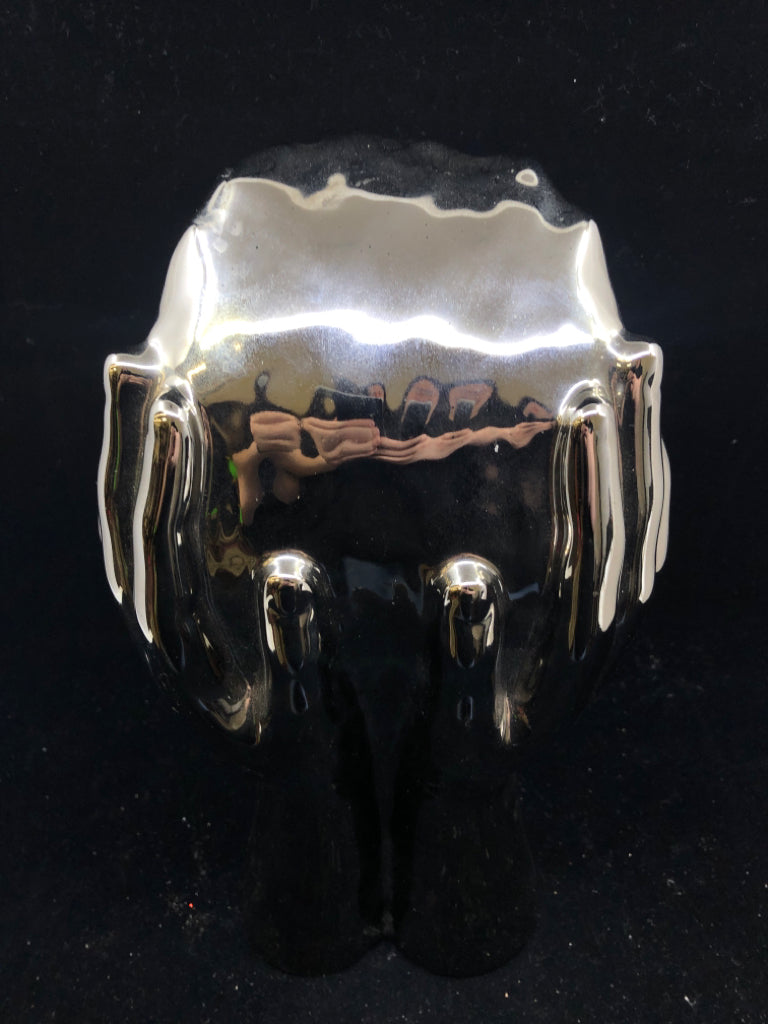 CERAMIC SILVER PERSON HOLDING UP THEIR FACE.