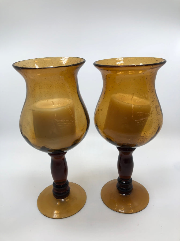 2 AMBER GLASS CANDLE HOLDERS W/WAX CANDLES.